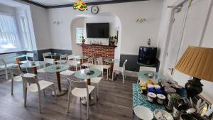 a dining room with tables and chairs and a tv at Gatwick Castle B&B in Horley