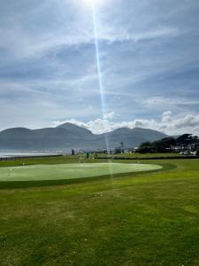 a green golf course with mountains in the background at The South Promenade apartment in Newcastle