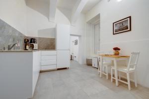 a kitchen with white cabinets and a table and chairs at Comfy 1 Bedroom in the Heart of Valletta in Valletta