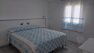 a bedroom with a bed with a blue and white comforter at Garden Hotel Alghero in Fertilia