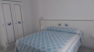 a bedroom with a bed with a blue and white comforter at Garden Hotel Alghero in Fertilia