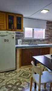 une cuisine avec une table et un réfrigérateur blanc dans l'établissement Cabaña Vivir, à El Chalten 3 autres photos