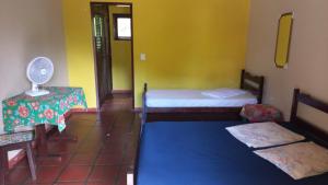a room with two beds and a table and a fan at Ubatuba's Surf hotel in Ubatuba