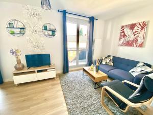 a living room with a blue couch and a tv at Le Maréchal, spacieux avec place de parking in Limoges