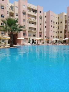 a large swimming pool in front of a large building at Appartement au rdc de la résidence Rosiers avec piscine à Monammedia in Mohammedia