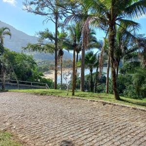 a cobblestone road with palm trees and a beach at Ubatuba's Surf hotel in Ubatuba