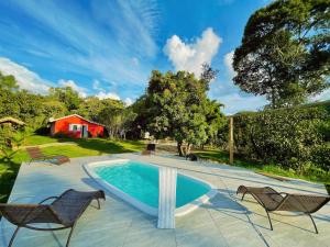 a swimming pool with two chairs and a house at Estalagem Cachoeira do Pimenta in Cunha