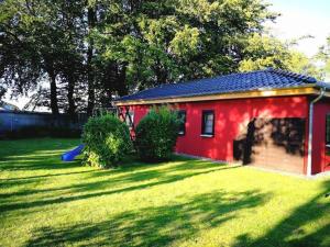a red shed in a yard with a grass field at Haus Eckstein in Lohme