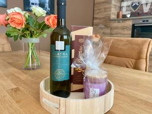 a bottle of wine sitting on a table with flowers at SUN Apartment in Dobrinj