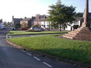 a street with a grass median in a town with houses at Boot & Shoe Inn in Greystoke
