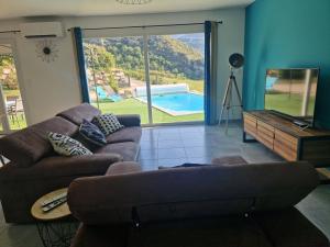 un soggiorno con divano e vista sulla piscina di Les Villas Dorées - Villa Métal face au Mont Ventoux a Plaisians