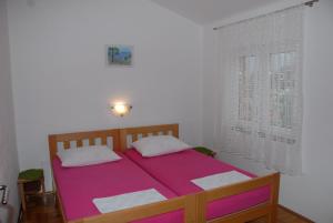 1 dormitorio con cama rosa y ventana en Apartments Kate, en Senj