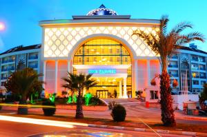 un grand bâtiment avec des palmiers devant lui dans l'établissement Side Prenses Resort Hotel & Spa, à Sidé