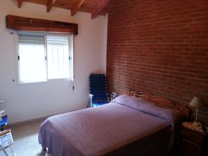 een slaapkamer met een bed en een bakstenen muur bij MaJoMi Toninas in Las Toninas
