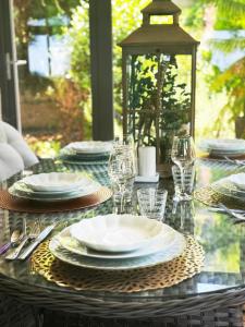 a glass table with plates and wine glasses on it at Au Pied du Frêne in Bourganeuf