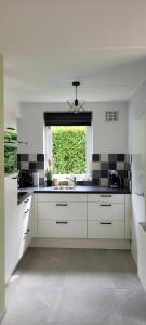 Una cocina blanca con fregadero y ventana. en Evergreen wellness met sauna & hottub, en Ewijk