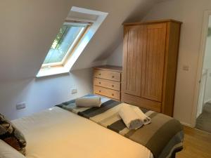ein Schlafzimmer mit einem Bett mit einer Kommode und einem Fenster in der Unterkunft Selwood Cottage in Beckington