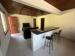 a kitchen with a counter and two bar stools at Chalé das Mangueiras in Itatiaia