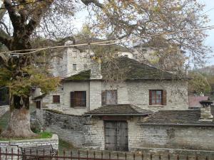 una vieja casa de piedra con un árbol delante en Archontiko Tzoufi en Kapesovo