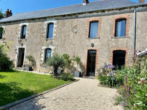 an old stone house with a garden in front of it at La Grange du presbytère in Mouzeil