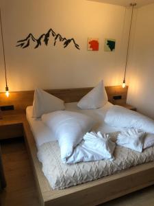 Una cama con sábanas blancas y montañas en la pared. en Zur Stella, en Presseggen