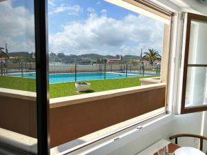 a window with a view of a swimming pool at Tu lugar en la playa in Luanco