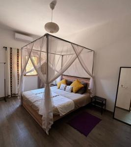 a bedroom with a canopy bed with yellow pillows at Villa Idaka in Rufisque