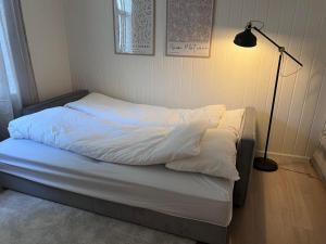 a bed with white sheets and a lamp in a room at Koselig leilighet i Ålesund sentrum in Ålesund