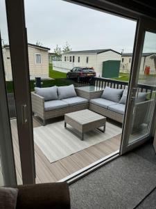 a patio with two couches and a coffee table at Golden Palm Resort - The Superior Retreat - Coastal Caravan Breaks in Chapel Saint Leonards