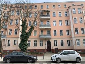 Dos coches aparcados delante de un gran edificio. en Hostel w centrum Szczecina 4 osobowe pokoje, en Szczecin
