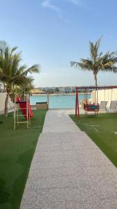 a park with a playground with palm trees next to the water at فيلا السعادة بشاطي خاص درة العروس in Durat Alarous