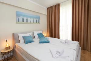 a bedroom with a large white bed with blue pillows at Bellicity Apart Complex in Ravda +89 photos