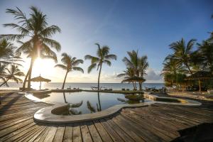 a pool on the beach with palm trees and the ocean at Waterlovers Beach Resort in Diani Beach