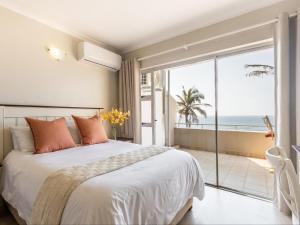 a bedroom with a bed and a view of the ocean at Beachfront Apartment Shakas Rock - Martinique, Pool, Ocean Views in Ballito