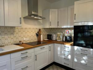 Maison calme au cœur de la Sainte Baume في سانت ماكسيمين-لا-سانت-بوم: مطبخ فيه دواليب بيضاء واجهزة سوداء +28 صورة