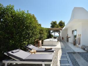 eine Terrasse mit Liegestühlen und Loungesesseln in der Unterkunft Olympa Suites in Plaka