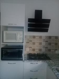 a kitchen with a microwave and a stove at à louer maison à la corniche les grottes de bizerte in Dar el Koudia