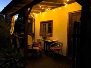 a patio with a table and chairs and lights at Domek przy Azylu Bocianim in Hutna Wieś +6 photos