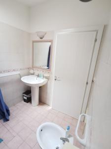 a white bathroom with a sink and a mirror at La payara di nonna nina in Tiggiano