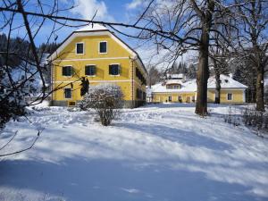 ein gelbes Haus mit Schnee davor in der Unterkunft Lindenhof in Murau