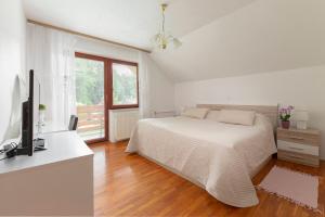 a white bedroom with a bed and a television at Fine Stay Apartments in Žirovnica +37 photos