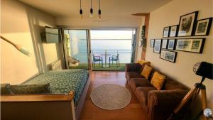 a living room with a bed and a couch at - L'IROIZH - CONCARNEAU - VUE MER PANORAMIQUE - STUDIO STANDING PLAGE DES SABLES BLANCS - PARKING - DRAPS & SERVIETTES INCLUS - NEAR THALASSOTHERAPY - Wifi - in Concarneau