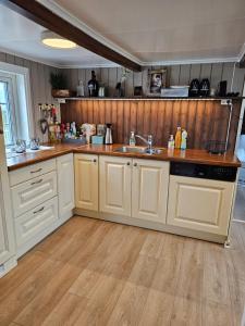 cocina con armarios blancos y suelo de madera en Fishermans Lodge Lofoten, en Hov