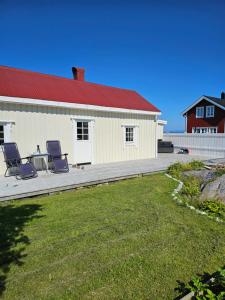 un edificio con 2 sillas y una mesa en un patio en Fishermans Lodge Lofoten, en Hov