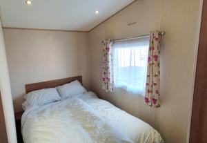 ein kleines Schlafzimmer mit einem Bett und einem Fenster in der Unterkunft Oxley Retreat, West Sands, Seal Bay Resort in Selsey