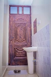 a bathroom with a sink and a wooden door at Stunning one bedroom unit in Ruiru with free parking in Ruiru