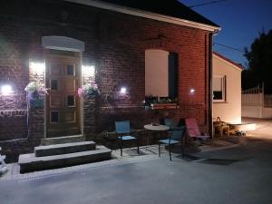 a brick building with a table and chairs next to a door at Gîte à la ferme Chez Magali in Cambrai
