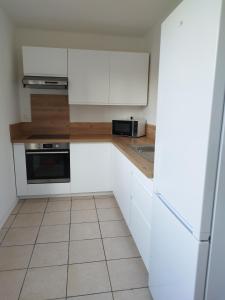a kitchen with white cabinets and a tile floor at Appartement traversant 2 chambres in Ajaccio
