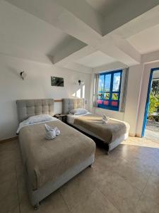 a bedroom with two beds and a large window at Hotel El Jardin in Salento