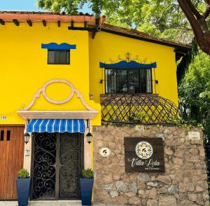 a yellow house with a sign in front of it at Villa Lola - Adults Only in Puerto Vallarta